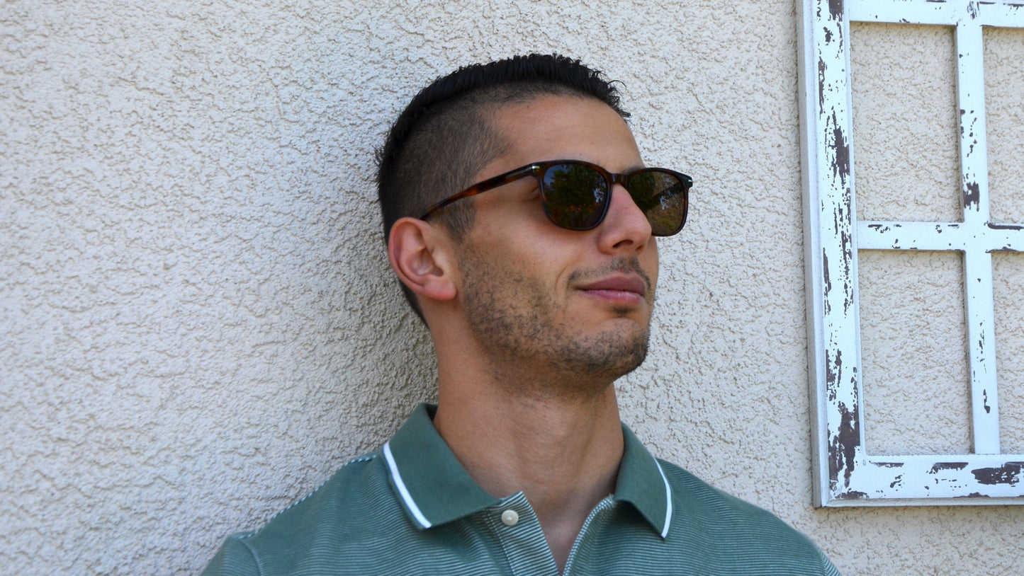 Good looking man wearing Merhoki Astor wayfarer eyewear, standing by vintage white frame.