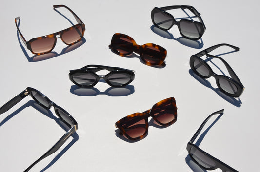 Pile of eight brown and black sunglasses arranged in different angle and positions