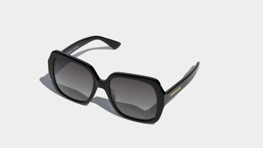 Angled front view of shiny black butterfly style frame sunglasses with grey square lenses