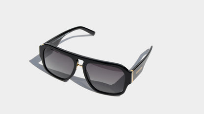 Angled front view of black style navigator frame sunglasses with grey square lenses