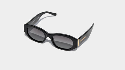 Angled front view of shiny rectangle frame sunglasses with narrow grey lenses