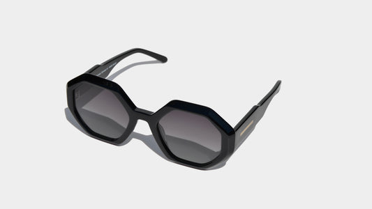 Angled front view of black geometric frame sunglasses with grey round lenses