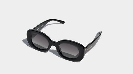 Angled front view of black rounded cat eye frame sunglasses with grey oval lenses