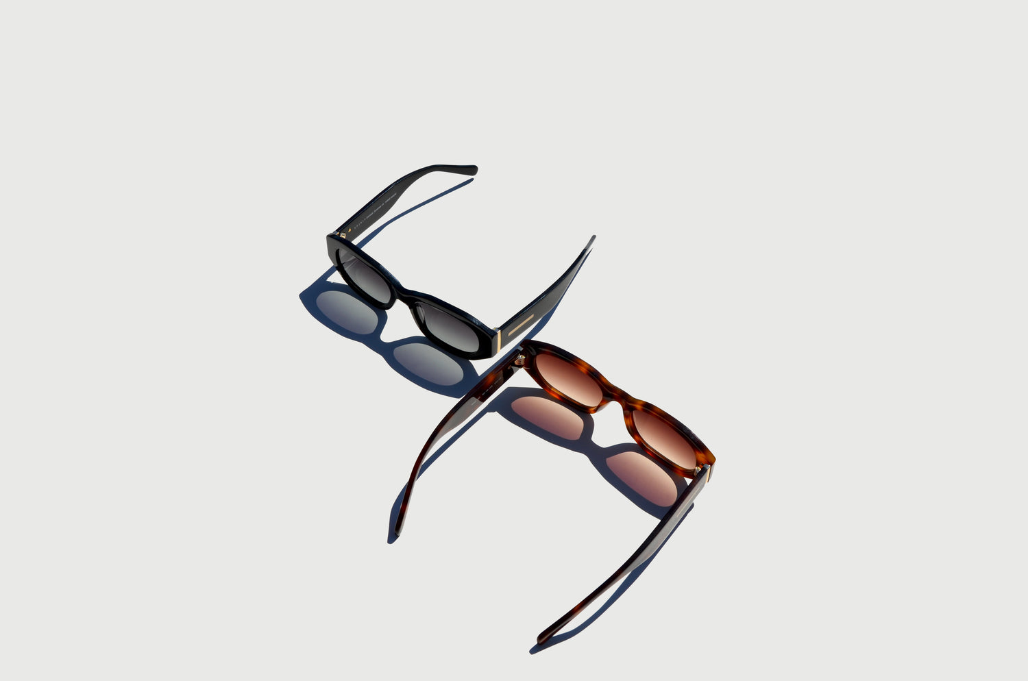 Two sunglasses brown and black rectangle frames mirroring each other