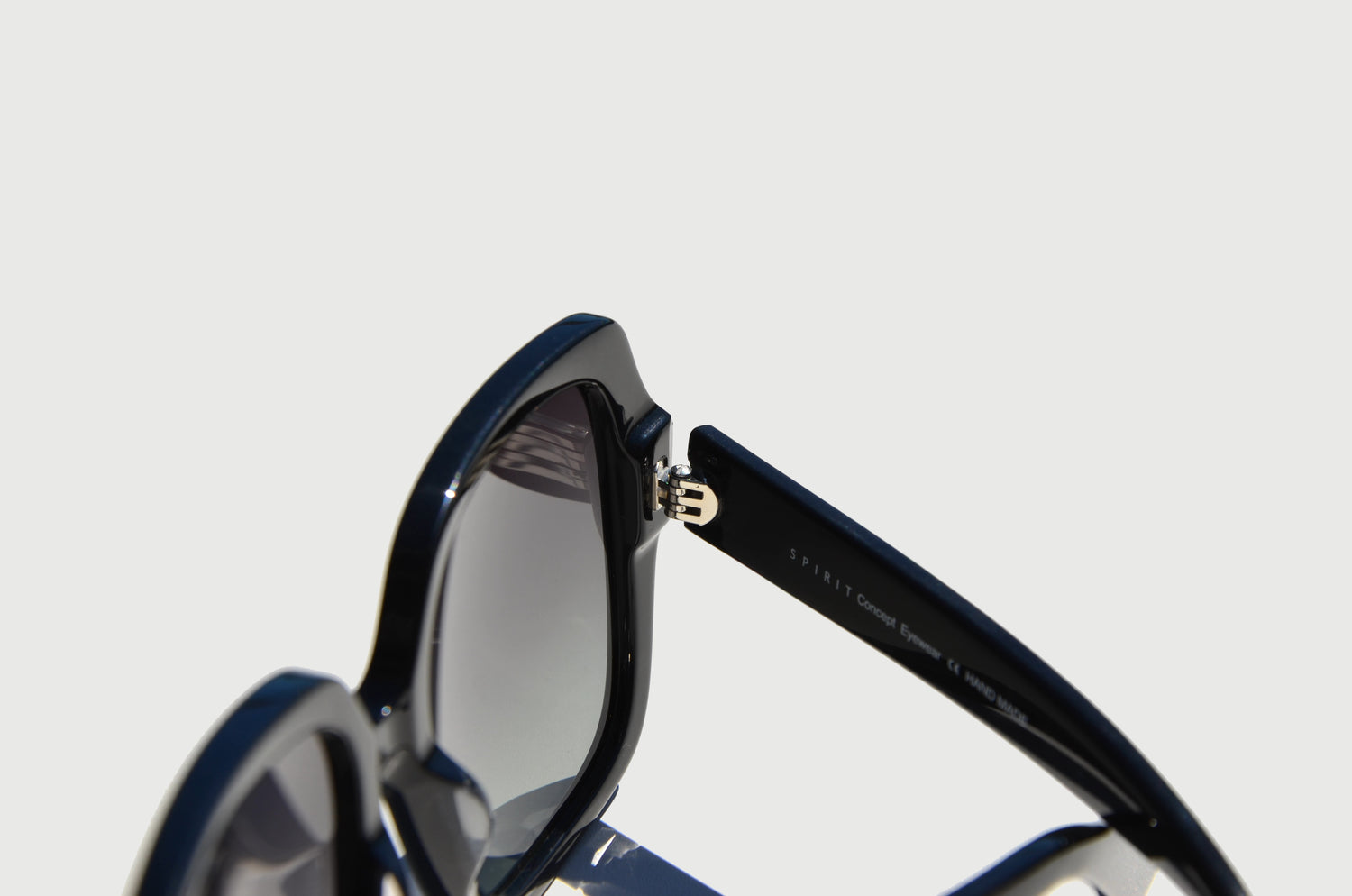 Zoomed in view of black sunglasses folded at hinge connected to large black lenses