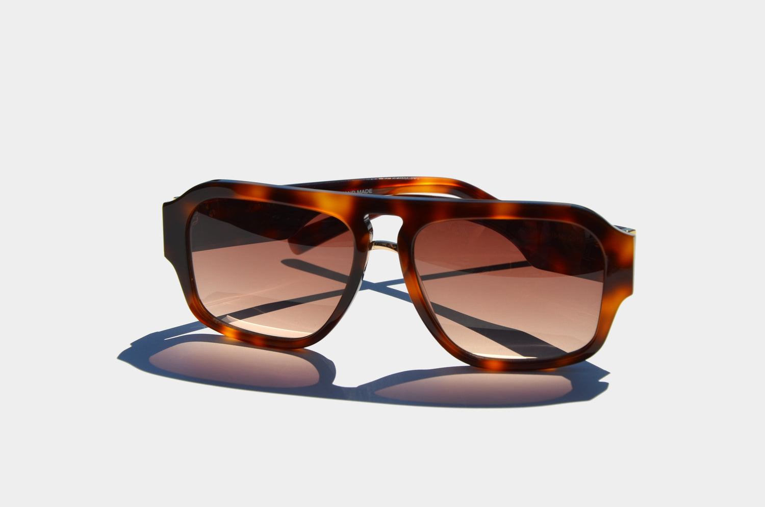 Brown double bridge sunglasses square lenses facing front with arms folded behind