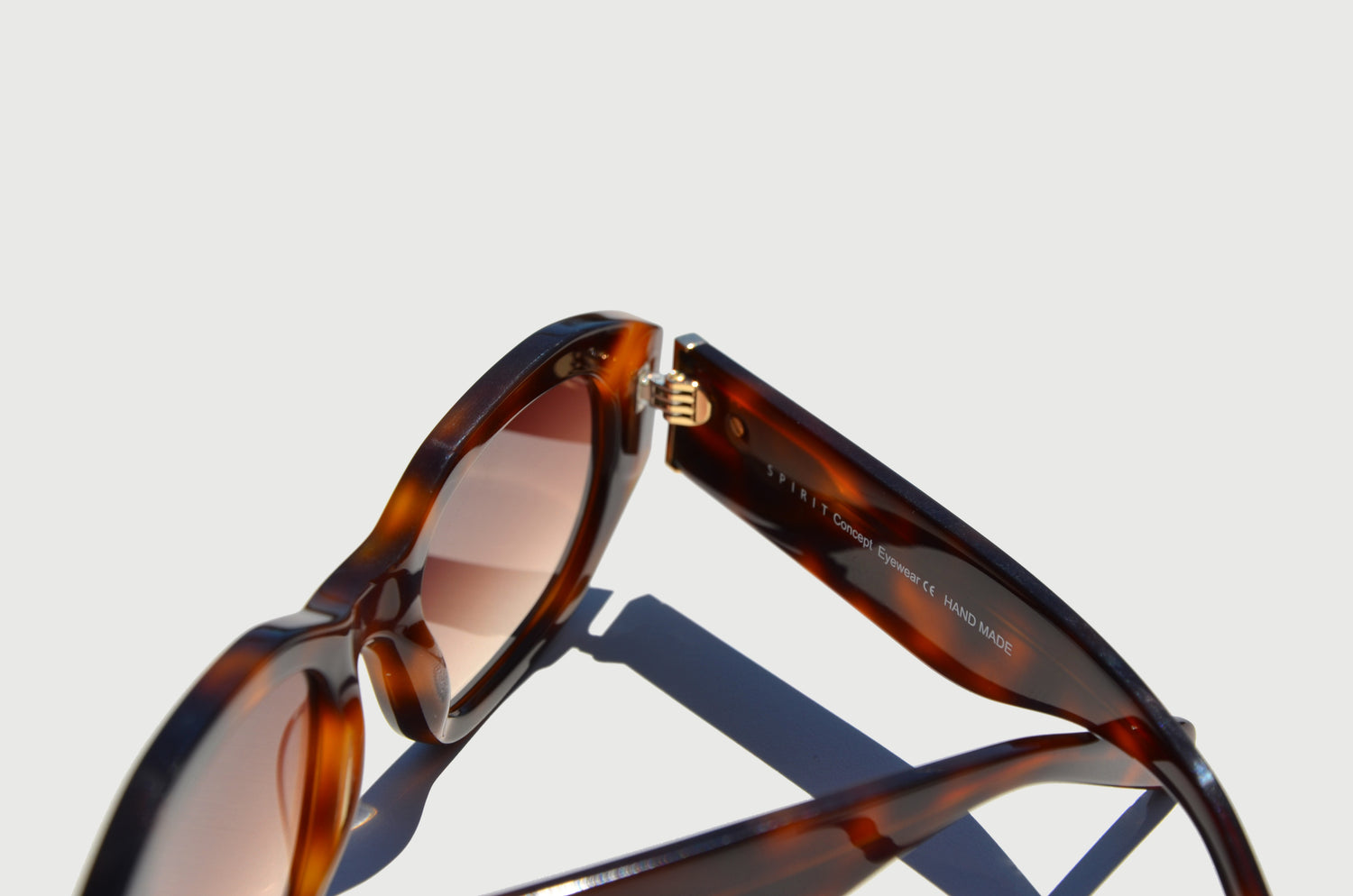 Brown sunglasses zoomed in on hinge connecting arm to rectangular frame