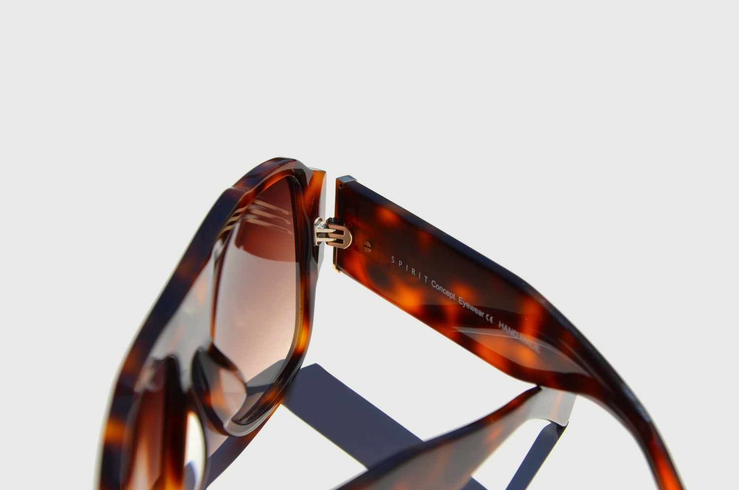 Close-up of brown sunglasses detailed hinge and arm, with Spirit Concept Eyewear on the inside