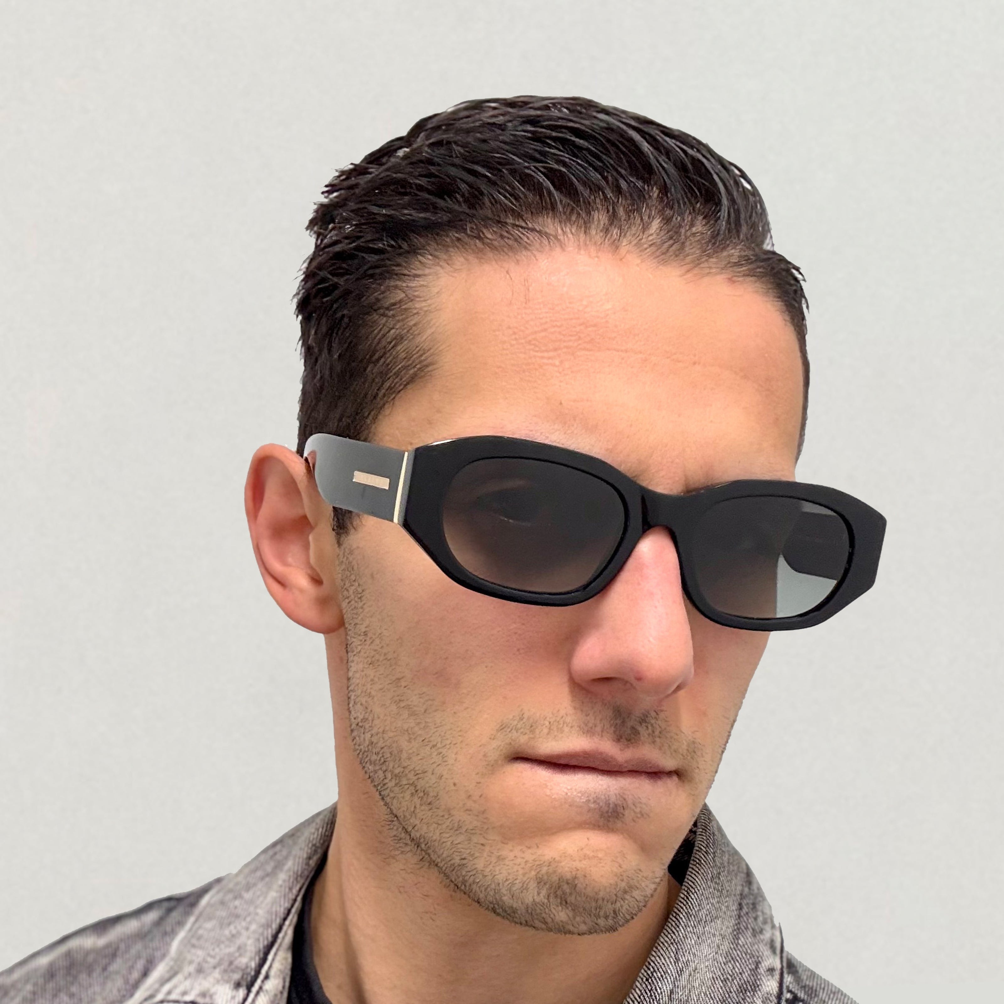 Rebellious edgy man wearing sleek black rectangular eyewear.