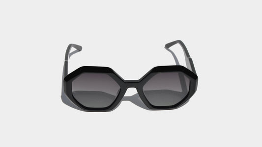 Front view of Shiny black eyewear with bold geometric frames and oversized gradient grey lenses, blending retro-futurism with Milan style.