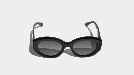 Front view of shiny black rectangle frame sunglasses, combining a minimalist silhouette with a sleek, high-gloss finish.