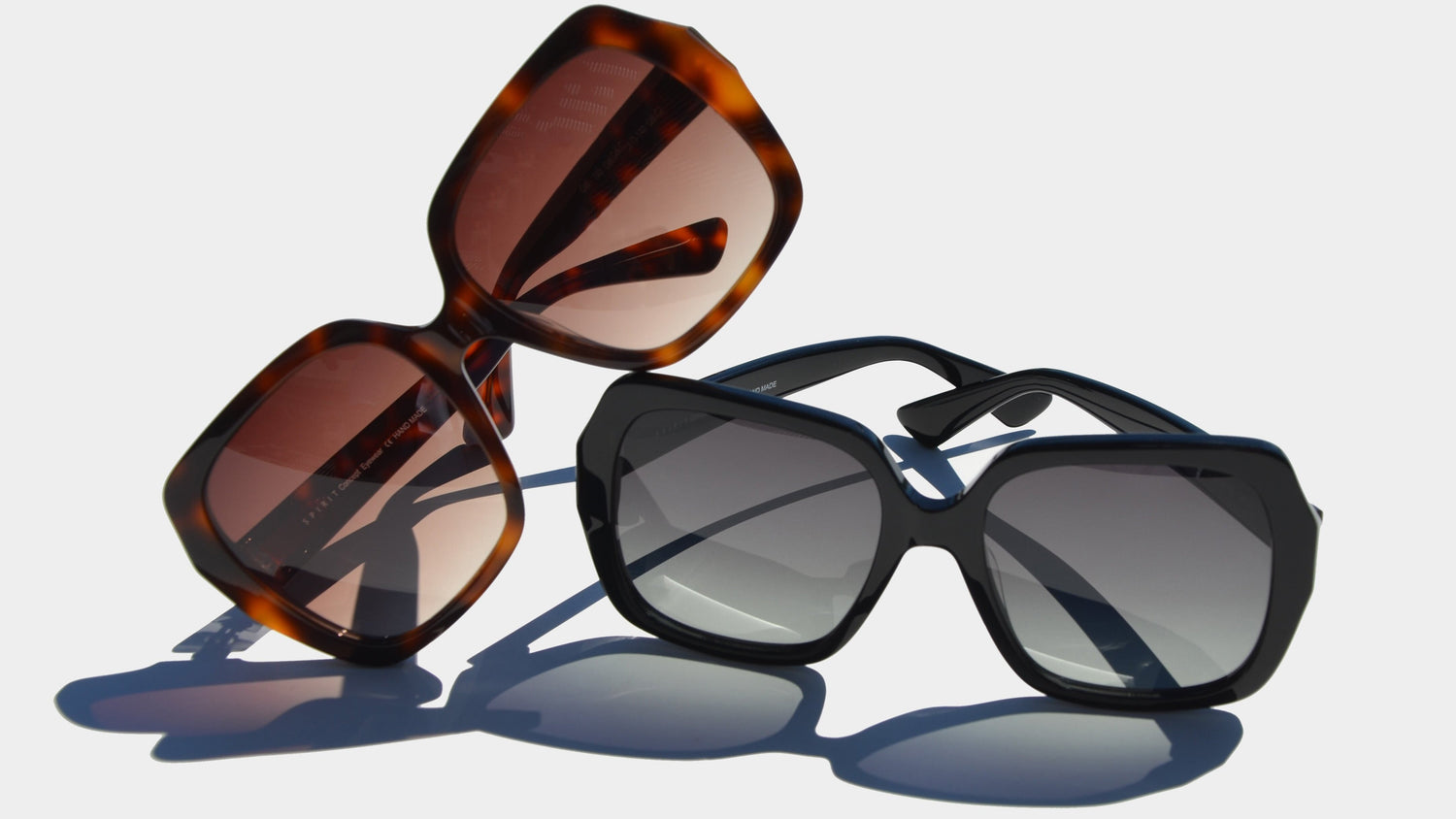 A bold display of two square-style eyewear pieces against a light background. The Havana eyewear, featuring rich frames and warm amber-tinted lenses, leans dramatically to the left. The black eyewear with gradient gray lenses is placed on the right, offering a sleek and modern aesthetic. 